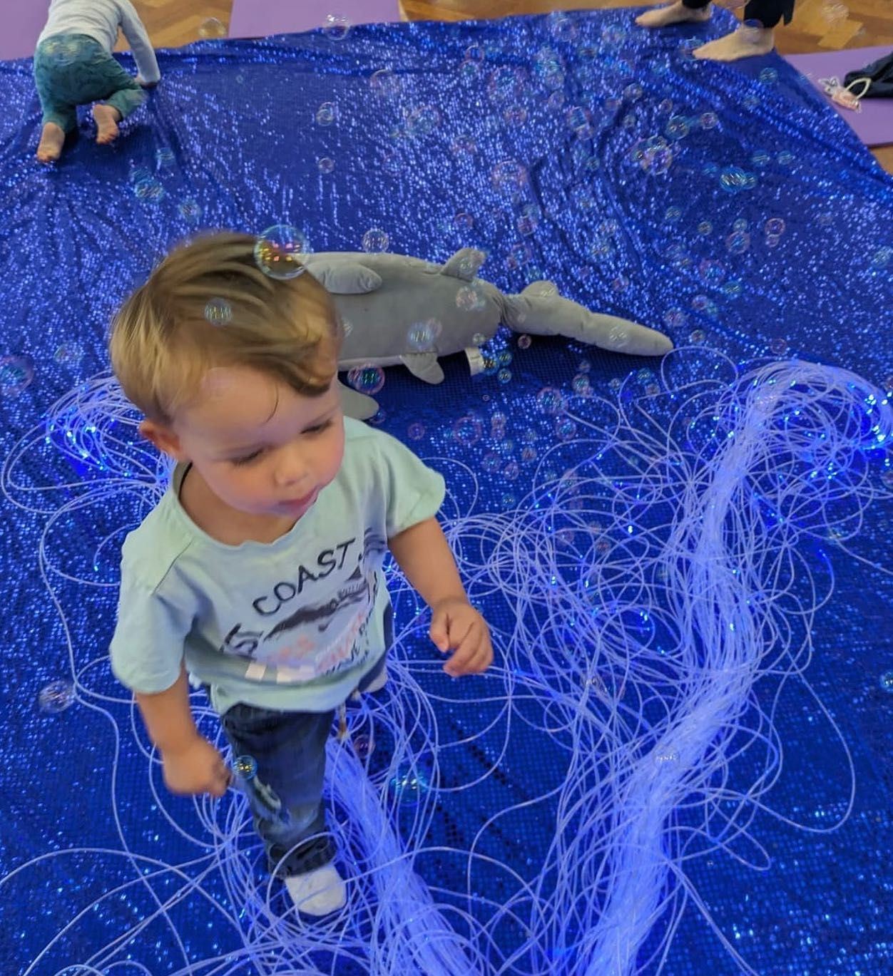A toddler exploring a blue sensory play area