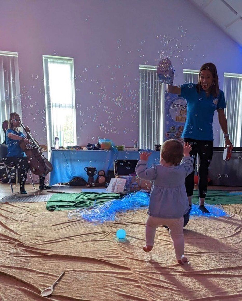 A StoryBox leader making bubbles for a toddler